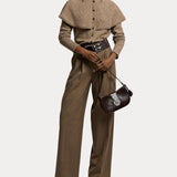A person wearing the RALPH LAUREN COLLECTION Cashmere Turtleneck Cardigan Sweater layered over a collared shirt, paired with wide-leg brown trousers and heeled shoes, holds a dark brown purse while posing against a plain white background.