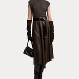A woman wears the RALPH LAUREN COLLECTION Cashmere Turtleneck Sleeveless Sweater, paired with a belted midi skirt, long leather gloves, knee-high boots, and carries a small black handbag. The ensemble features dark tones for a sophisticated look against a white background.