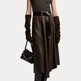 A person wearing a RALPH LAUREN COLLECTION Cashmere Turtleneck Sleeveless Sweater, a wide leather belt, a midi skirt, elbow-length gloves, and tall boots, while carrying a small handbag with chain detail.