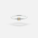The SPINELLI KILCOLLIN Sirius 3 Annulets Ring is a minimalist unisex sterling silver band featuring two silver beads flanking a gold bead, set against a plain white background—perfect for modular jewelry styling.