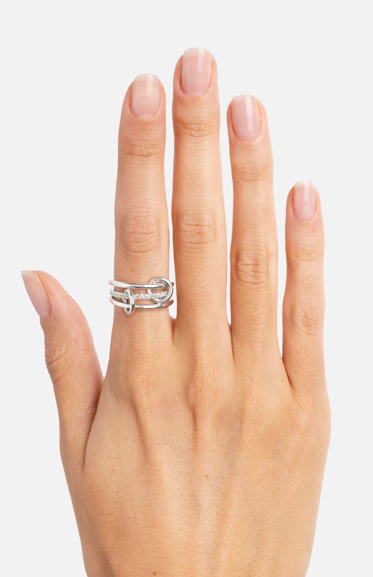A hand with neatly manicured nails displays the SPINELLI KILCOLLIN Sonny Pavé Band Ring—a chunky, linked double-band sterling silver ring—worn on the middle finger against a plain white background.