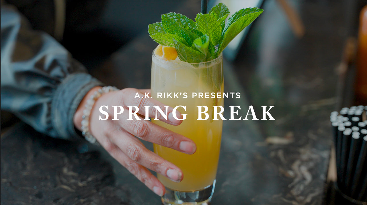 image with text "A.K. Rikk's presents Spring Break" image is of a tropical yellow cocktail with a lemon and mint sprig on top