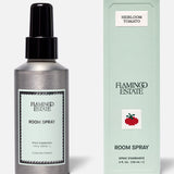 A silver spray bottle and a light green box labeled FLAMINGO ESTATE Roma Heirloom Tomato Room Spray—with the signature tomato illustration—are displayed against a plain background, capturing the fresh, vibrant essence of a summer garden to create an inviting home fragrance experience.
