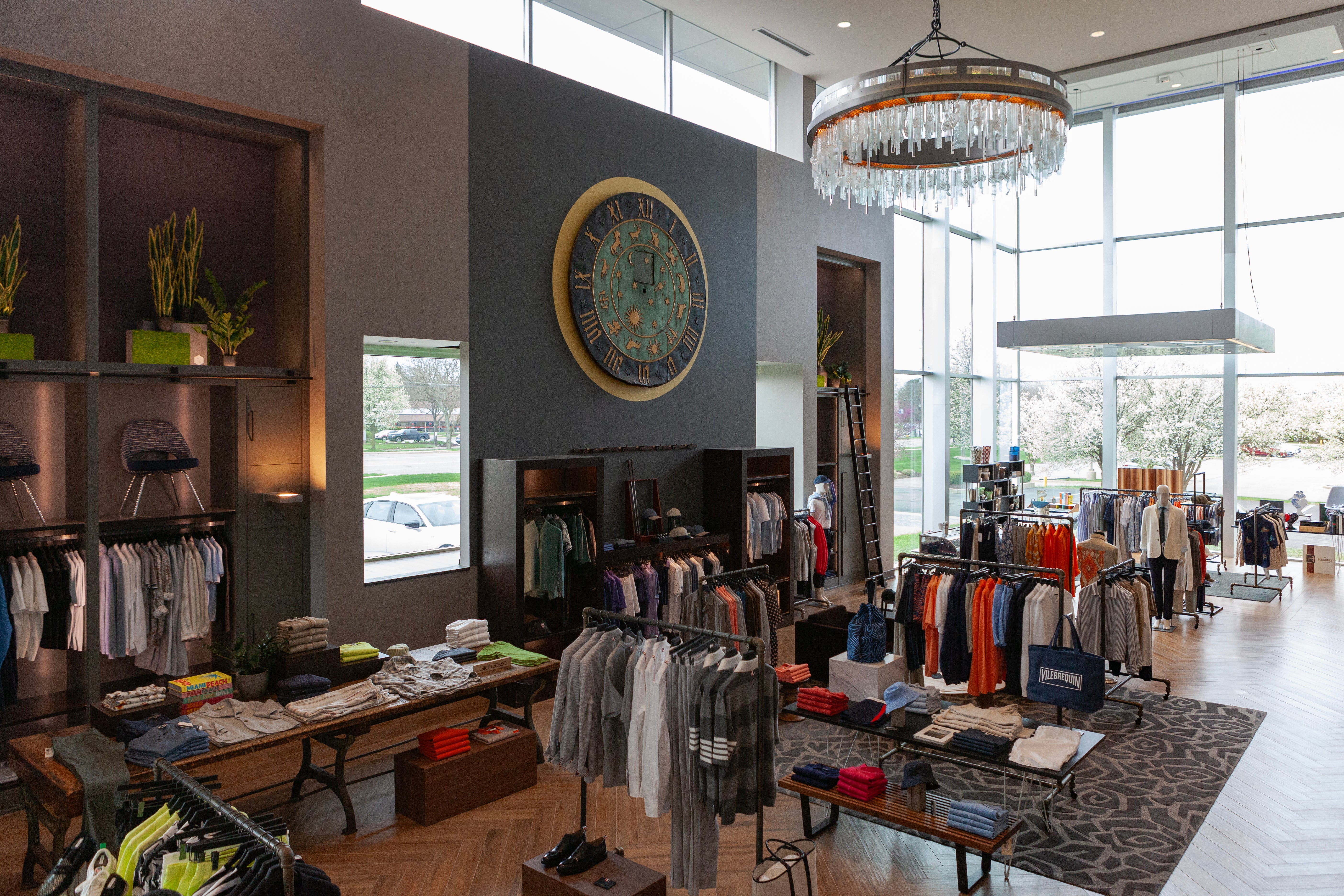 Modern clothing store interior with racks of clothes and a chandelier.