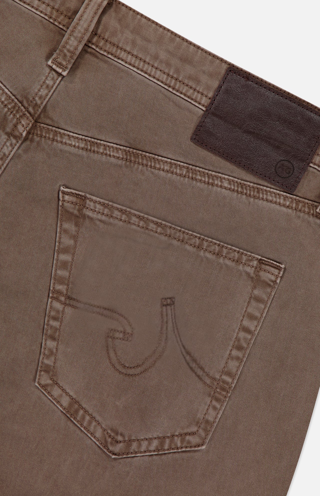 Close-up of the back pocket and waistband of AG Everett Slim Colored Jeans in grey-brown, highlighting decorative pocket stitching and a dark brown leather patch on the waistband.