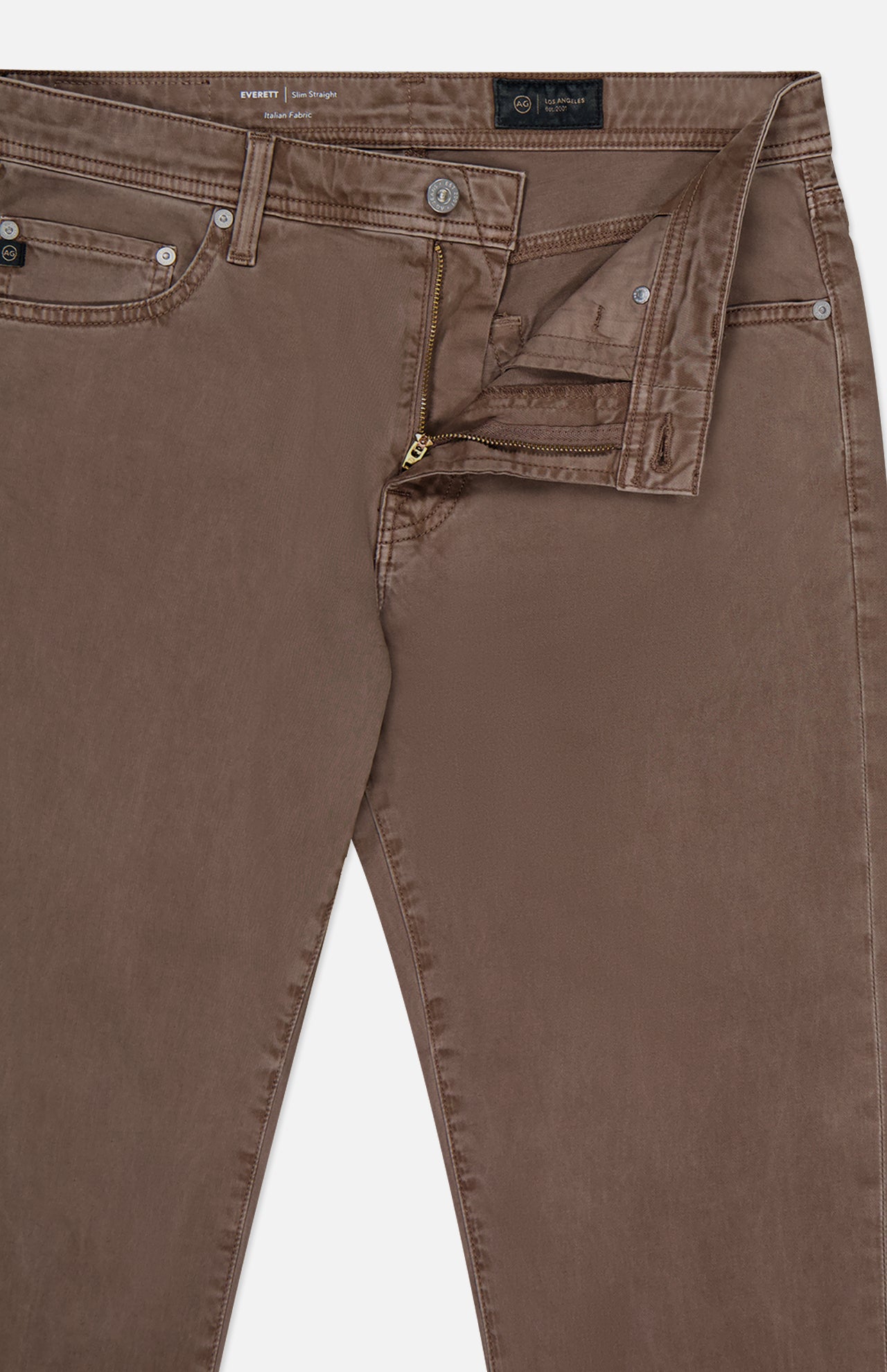 The image shows the top front of AG Everett Slim Colored Jeans in brown, featuring a partially open zipper and button fly, with visible waistband, belt loops, and pockets.
