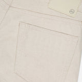Close-up of the back pocket on AG’s Everett Pants in cream-colored denim, slim straight fit, with a stitched pocket and a blank light leather patch featuring a small "AG" logo on the waistband.