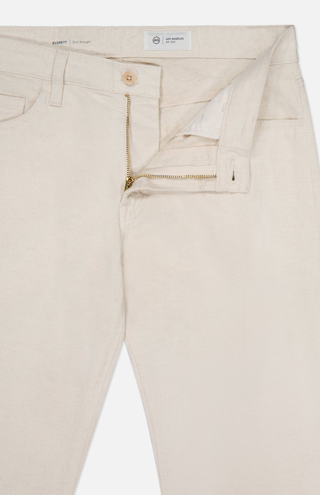 The Everett Pants by AG are light beige slim straight fit jeans, shown with the zipper partially open to reveal the waistband, button, and front pockets against a white background.