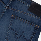 Close-up of the back pocket on the AG Everett Jean in 5 Years: dark blue slim fit denim with curved dark stitching and a black leather patch on the waistband.