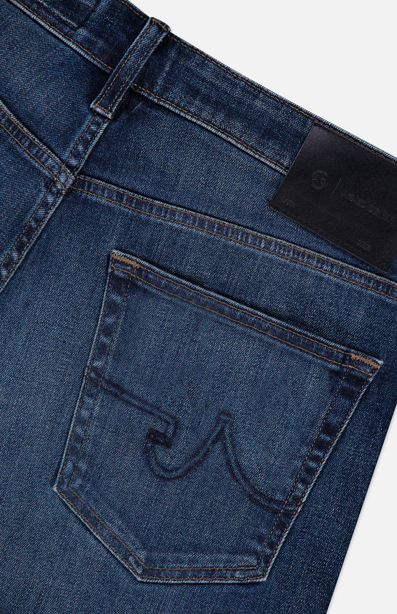 Close-up of the back pocket on the AG Everett Jean in 5 Years: dark blue slim fit denim with curved dark stitching and a black leather patch on the waistband.