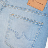 Close-up of AG's Everett Jeans in 22 Years: light blue wash slim fit style featuring a back pocket with stitched design, detailed seams, and a tan leather patch labeled “AG-ED DENIM” with lot and size fields.