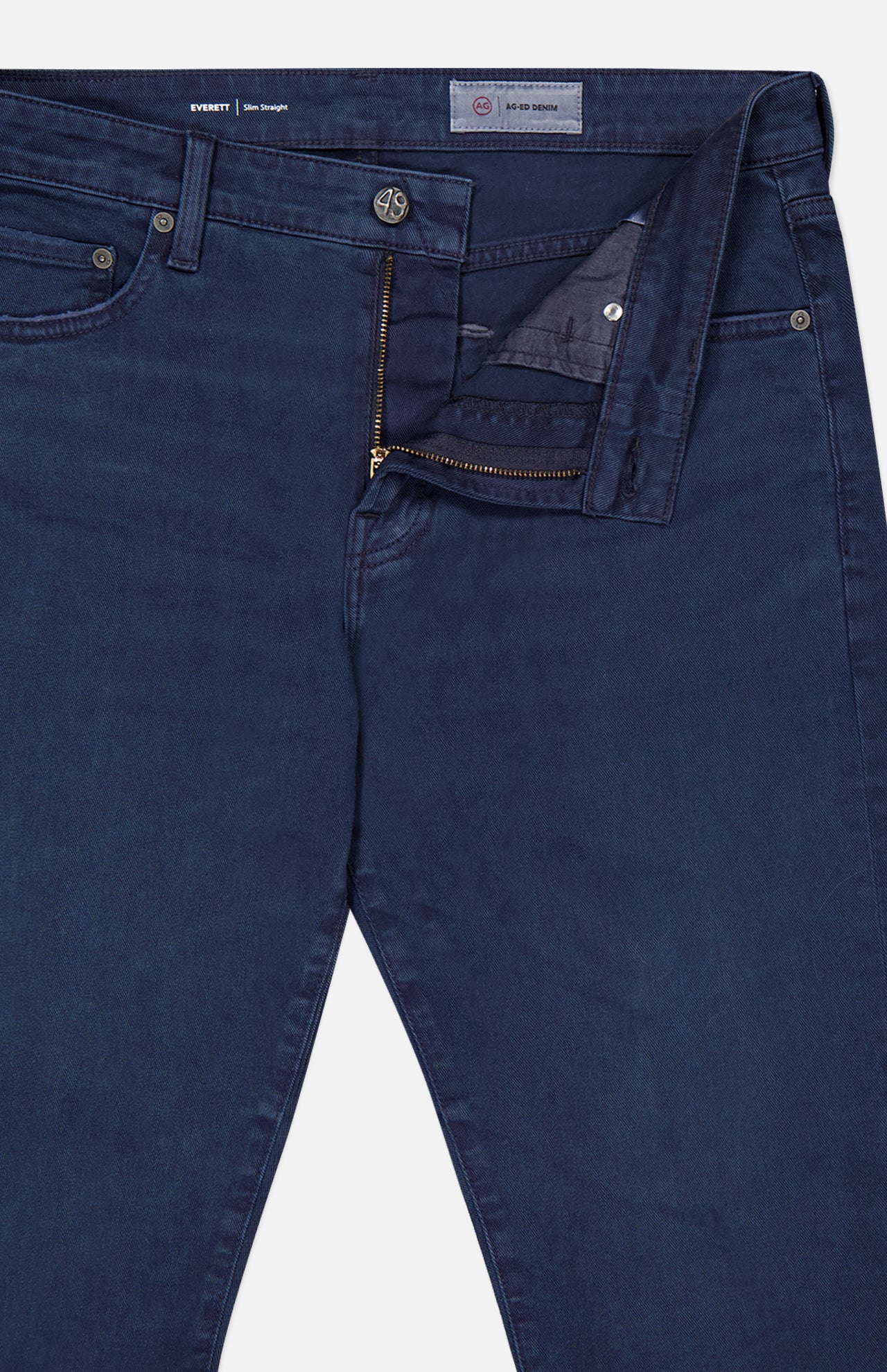 The Everett Slim Stretch Jeans by AG, in navy, feature a visible zipper fly and button closure, displayed partially unzipped and unbuttoned. These slim fit jeans are shown laid flat against a white background.