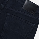 Close-up of the back pocket and waistband of the AG Everett Slim Corduroy Pant in dark blue, featuring a black leather brand patch and tonal stitching, highlighting its modern slim fit silhouette.