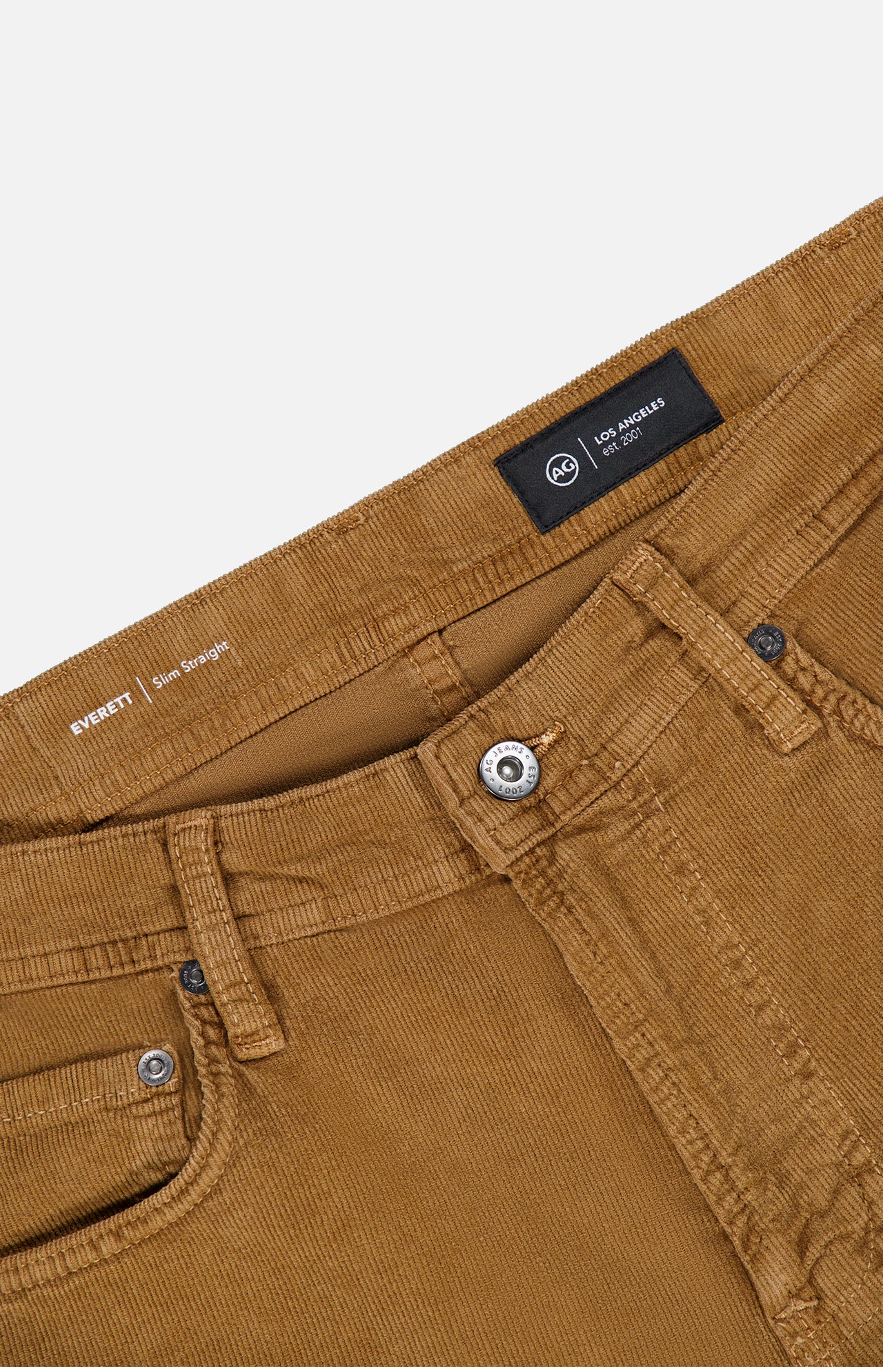 Close-up of the waistband and front pockets of the AG Everett Corduroy Pant in Bronze, featuring a slim fit, metal button, zipper, belt loops, and brand labels on the inside waistband, all set against a white background.