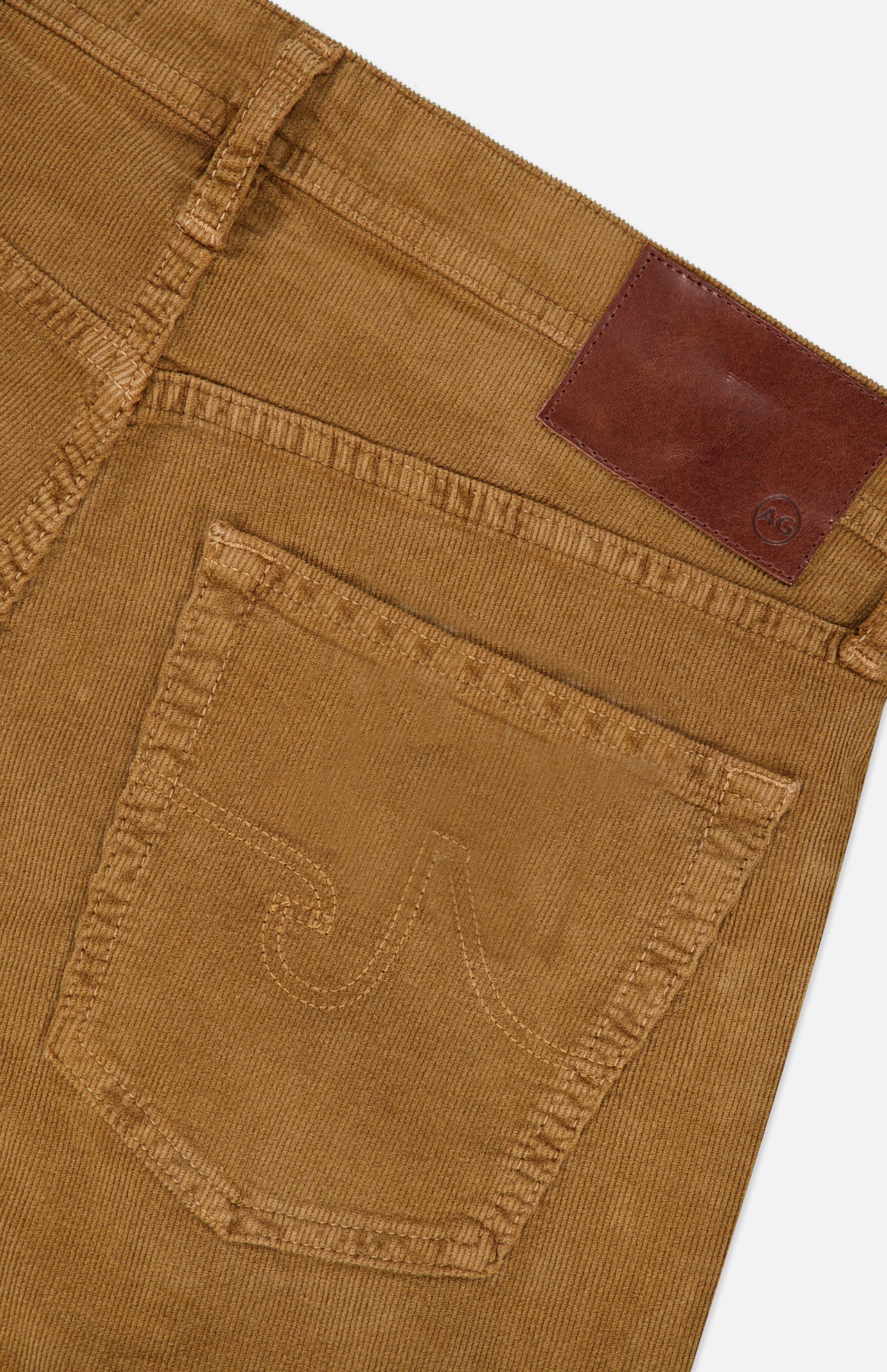 Close-up of the back pocket of the AG Everett Corduroy Pant in Bronze, featuring a stitched design and a brown leather patch above the pocket, highlighting its distinctive bronze hue.