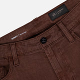 Close-up of the waistband and front pockets of AG's Everett Pants in Sulfur, showcasing a black button, belt loops, and an inner label with text including “Everett,” “Slim Straight,” and slim fit details.