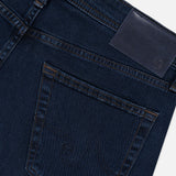Close-up of the back pocket and waistband of the AG Graduate Pant in Studio, featuring ultra-dark blue denim with visible stitching, vintage detailing, and a blank leather patch on the waistband.