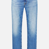 The Protege Jean in 14 Years by AG features light blue denim with a faded effect on the front thighs and knees, a classic five-pocket design, button and zipper closure, and a straight leg silhouette with subtle vintage detailing, shown against a white background.