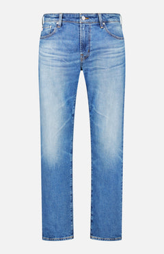 The Protege Jean in 14 Years by AG features light blue denim with a faded effect on the front thighs and knees, a classic five-pocket design, button and zipper closure, and a straight leg silhouette with subtle vintage detailing, shown against a white background.