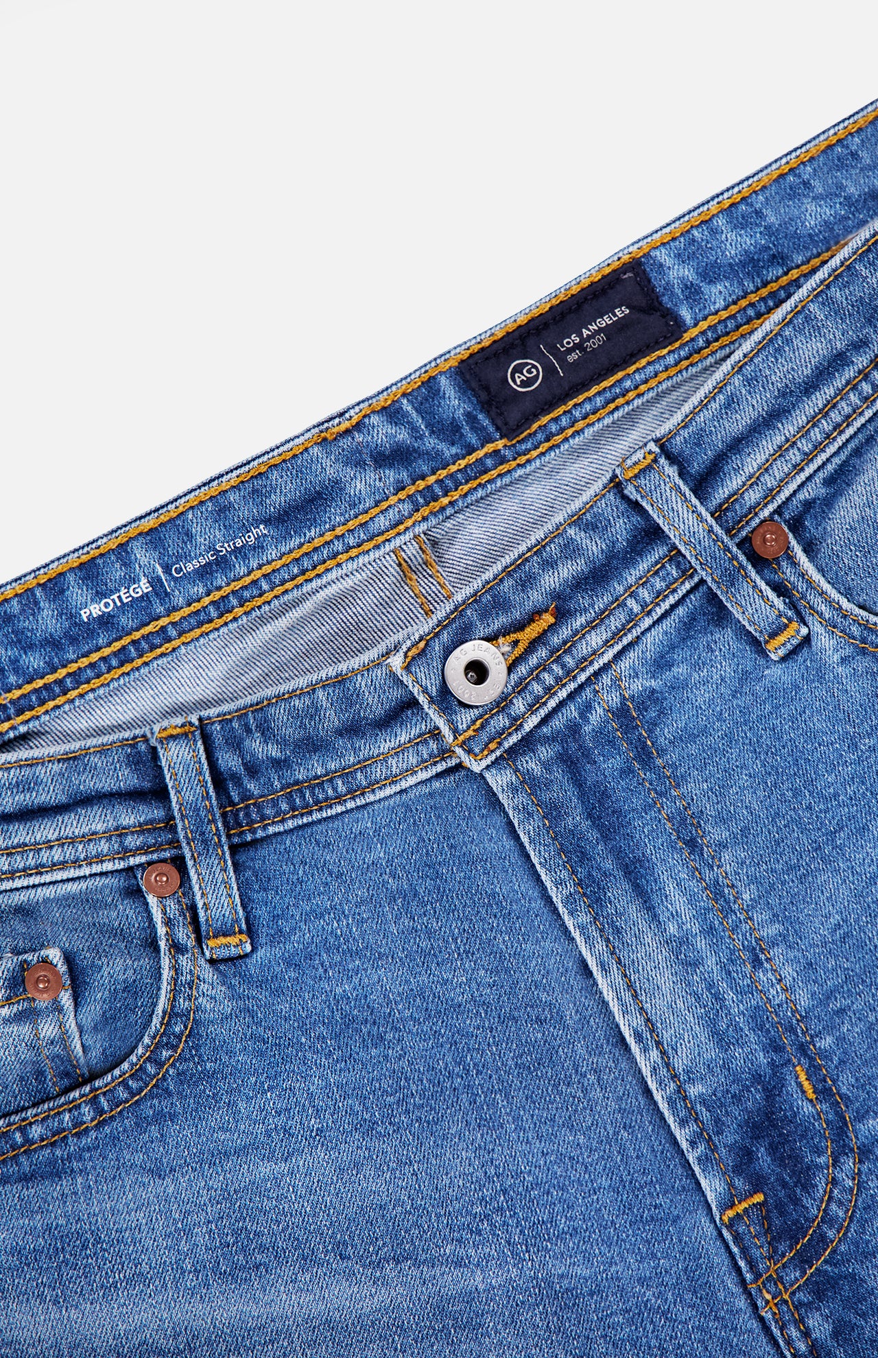Close-up of the waistband and upper section of AG's Protege Straight Leg Jeans in Promise, showing the button, zipper, belt loops, and front pockets against a white background.