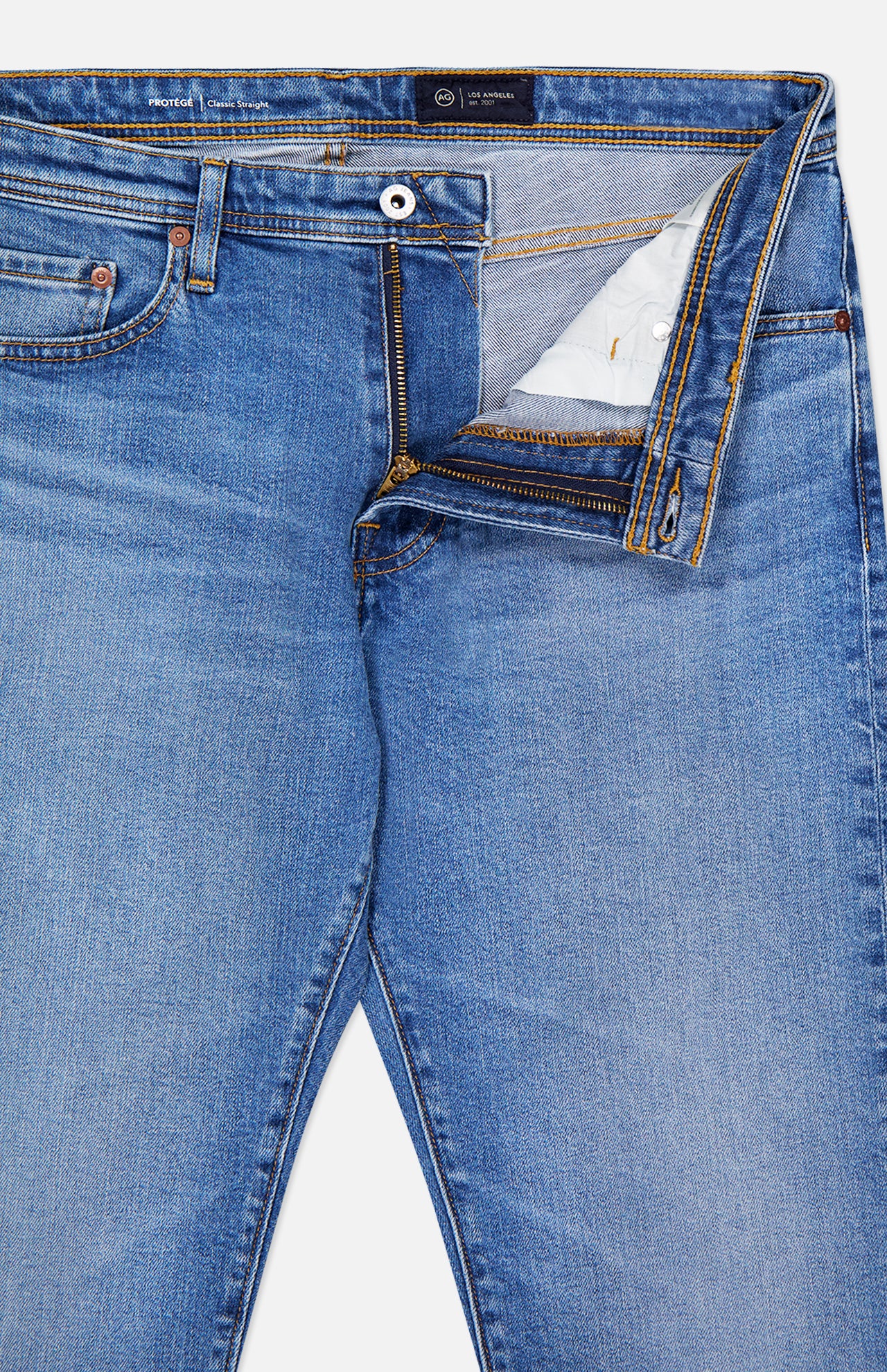 The AG Protege Straight Leg Jeans in Promise are light blue, comfortable stretch denim with classic yellow stitching, a partially open fly showing the zipper and button, visible inner waistband, and a front pocket rivet.