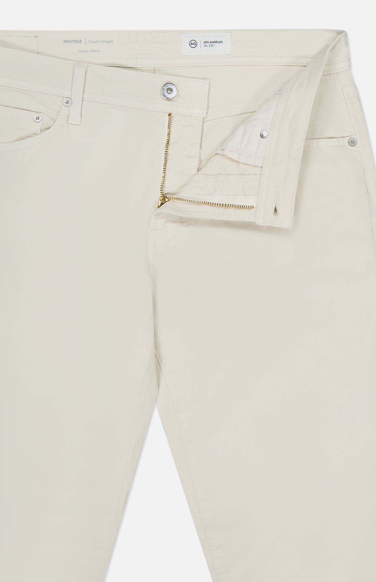 The AG Protege Pants in Pumice are off-white, straight leg denim pants with a partially unzipped fly, open waistband showing the button and inside label. They have front pockets, belt loops, and offer a comfortable stretch fit.