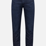 The AG Tellis Slim Jeans in Tamarack are dark blue men's jeans featuring a slim fit, five pockets, and belt loops, shown against a plain light gray background.