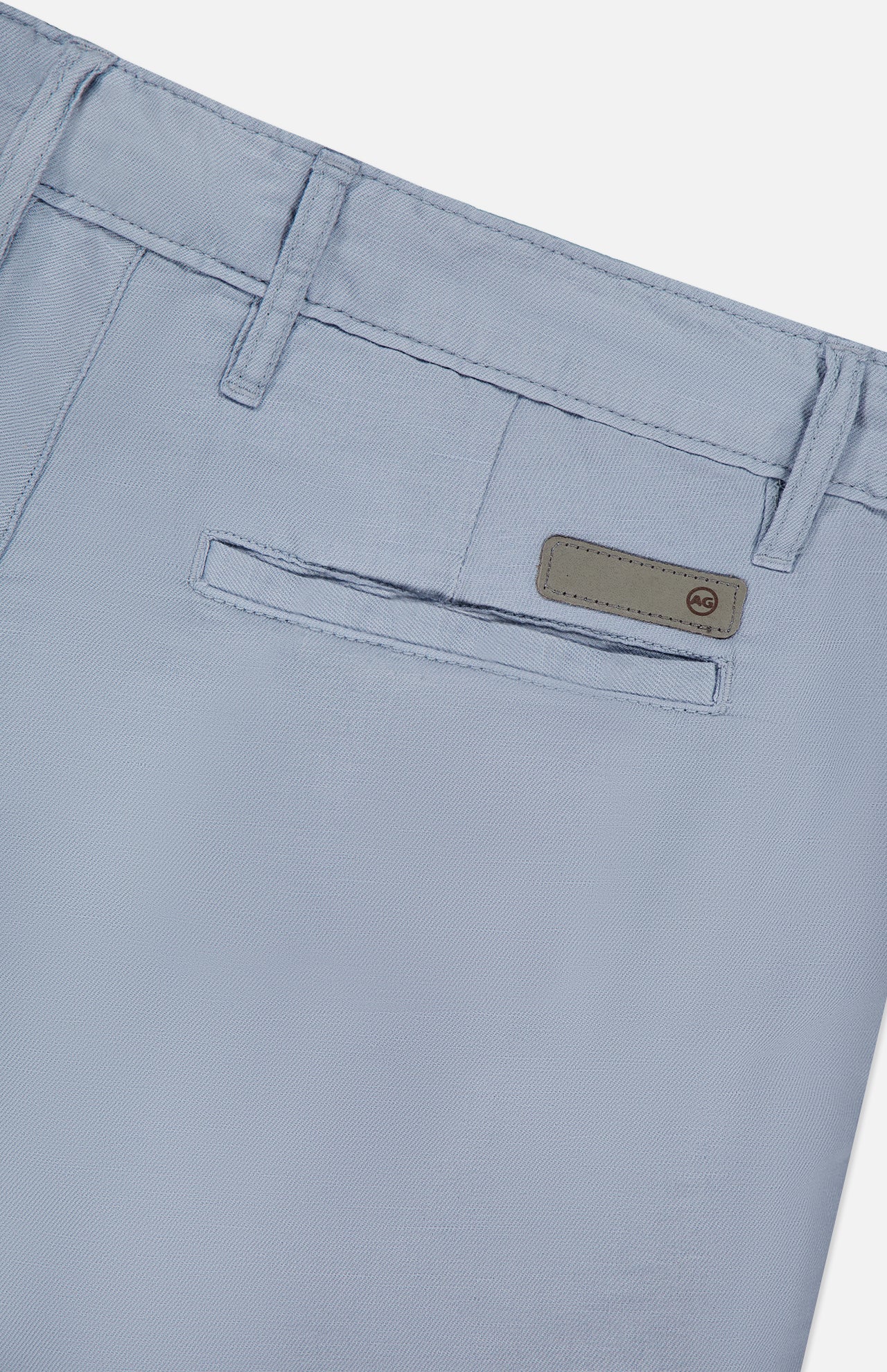 Close-up of the back pocket of AG Wanderer 8.5" Inseam Shorts in light blue, featuring a horizontal slit pocket, belt loops, and a small rectangular label above the pocket.