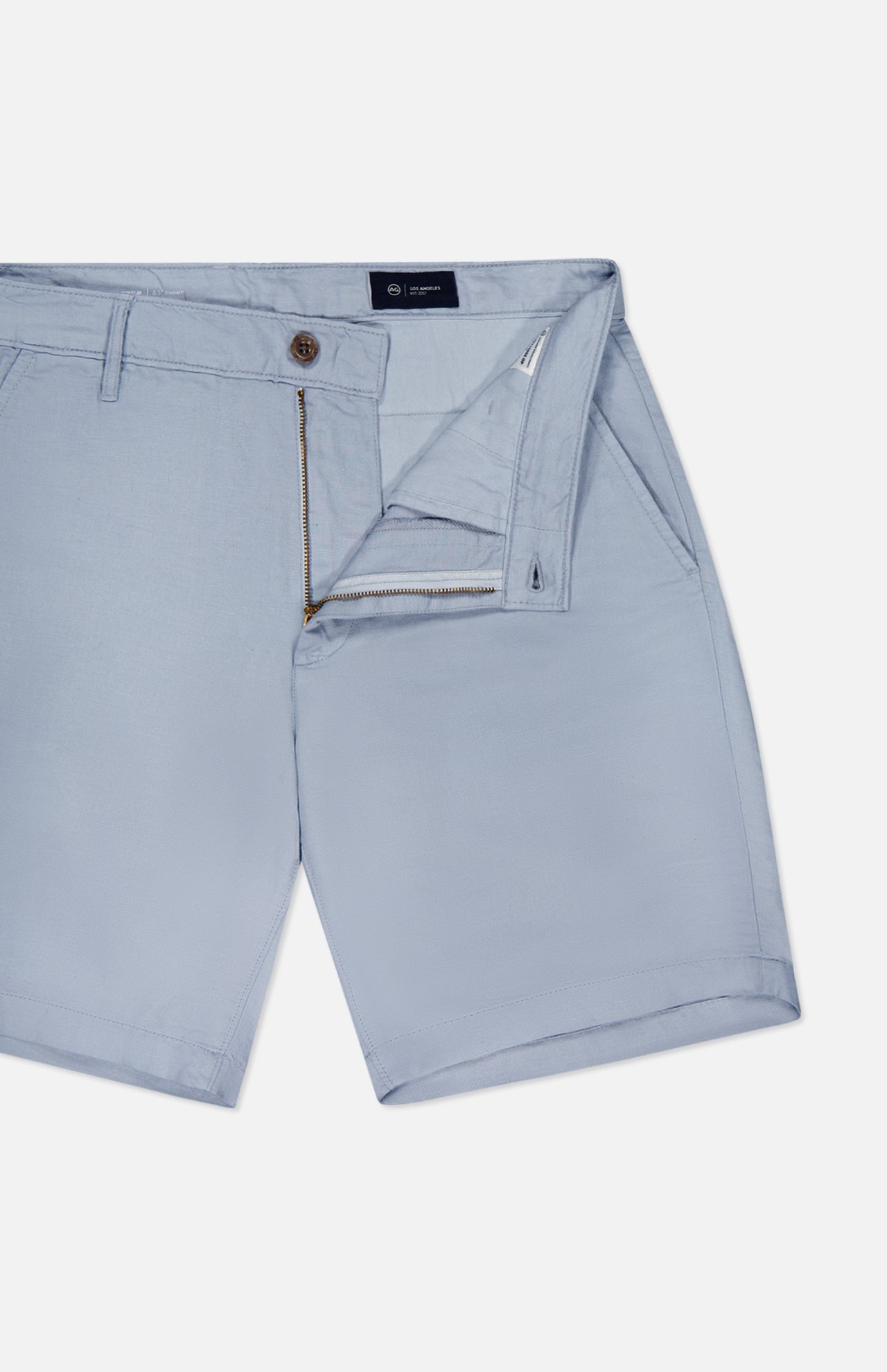 The AG Wanderer 8.5" Inseam Shorts for men in light blue feature a slim fit, front side pockets, belt loops, and a partially open button and zip fly, shown laid flat on a white background.