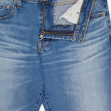 The Tellis Aged Jeans by AG are slim fit, light blue denim with a partially unzipped fly revealing the inner pocket lining and waistband label.