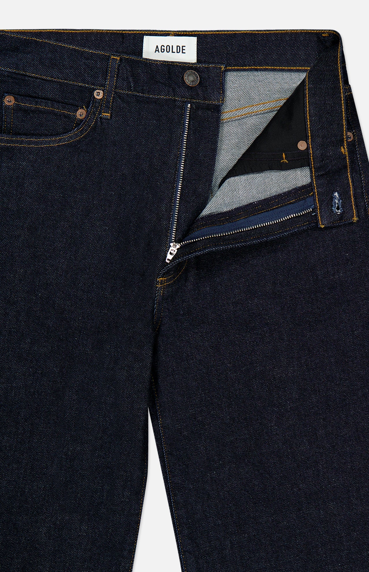Harper Jean in Reissue by AGOLDE shown in a dark indigo wash with a visible front zipper and button undone, revealing the inner waistband and pocket lining. The AGOLDE label is displayed on the inside waistband. These relaxed mid-rise jeans feature a straight leg silhouette for timeless appeal.