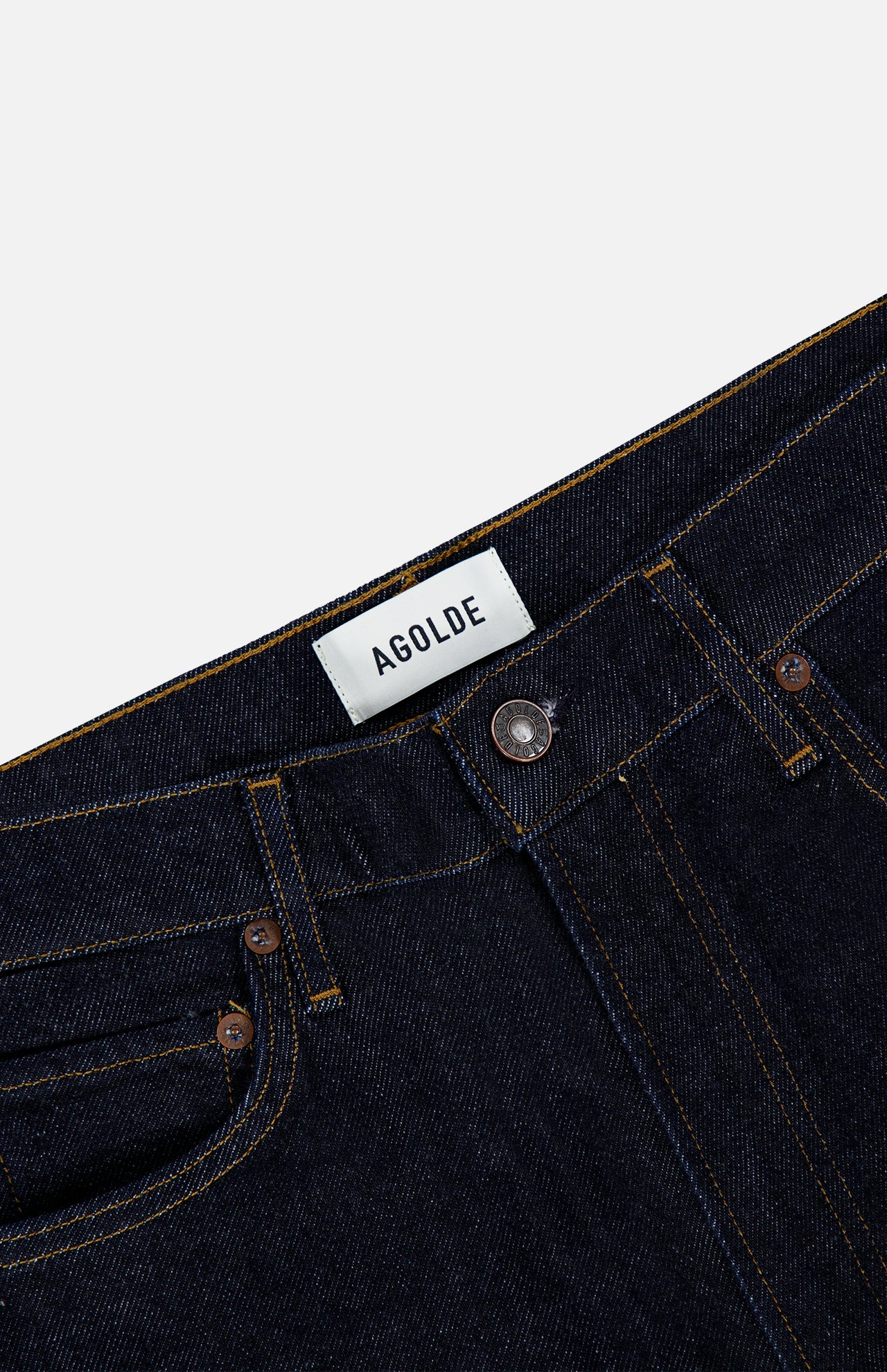 Close-up of the waistband and upper section of the Harper Jean in Reissue by AGOLDE in dark indigo, featuring yellow stitching and a white AGOLDE label, highlighting the signature details of these relaxed mid-rise jeans.