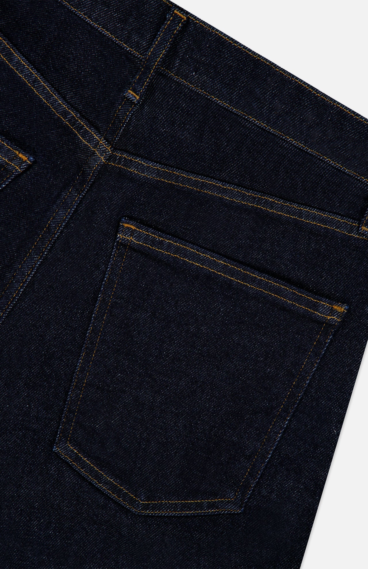 Close-up of the back pocket and stitching detail on the AGOLDE Harper Jean in Reissue, featuring one pocket and part of another with yellow thread. The straight leg dark indigo denim showcases classic construction and quality craftsmanship.