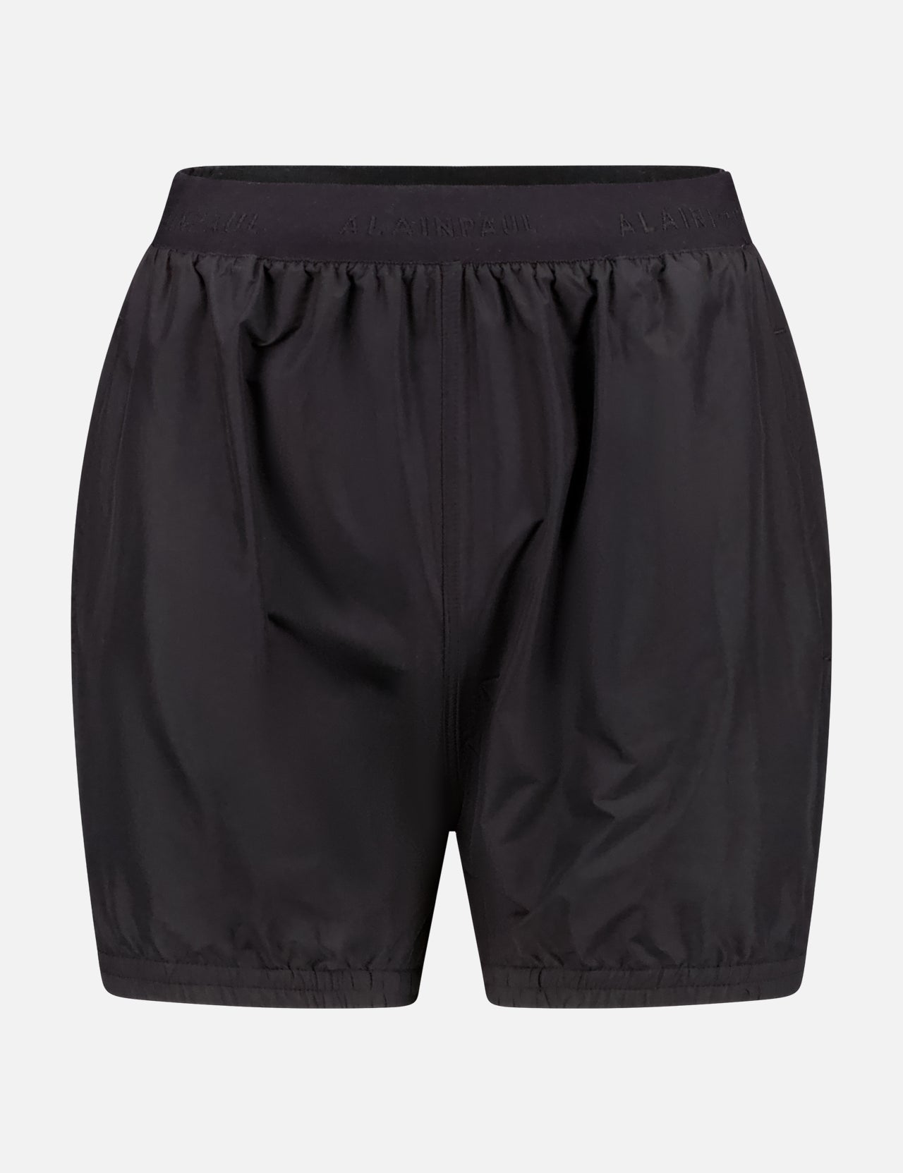 The ALAINPAUL Fuseau Track Shorts feature a loose fit and elastic waistband, inspired by track pants for sporty appeal, shown against a plain white background.
