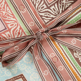 Close-up of the ALEMAIS Alberta Mini Linen Dress, showcasing a brown, pink, green, and blue geometric and floral print with a tied waist bow and small front buttons.