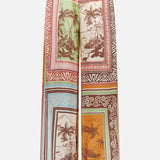 The Alberta Silk Pull-on Pant by ALEMAIS features a wide-leg, relaxed fit and a colorful patchwork of tropical palm tree and beach scenes. These bohemian silk joggers offer a comfy drawstring waist for easy wear.