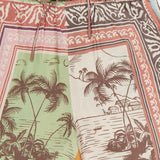 The ALEMAIS Alberta Silk Pull-on Pant features a relaxed fit and tropical patterns with palm trees, animals, and coastal scenery in earthy green, brown, red, and cream tones for a bohemian look.