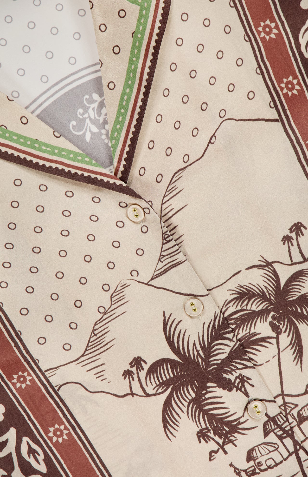 Close-up of the Alberta Silk Relaxed-fit Shirt by ALEMAIS, in patterned beige with brown buttons, featuring palm trees, car, mountains, polka dots, and earthy borders—perfect for resort wear.