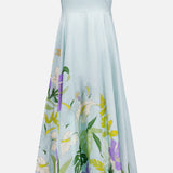 The Alfie Midi Floral Sundress by ALEMAIS features a pale blue base, yellow straps, and an artistic floral print with white, green, and purple flowers near the hem, finished with a brown trim along the bottom edge.