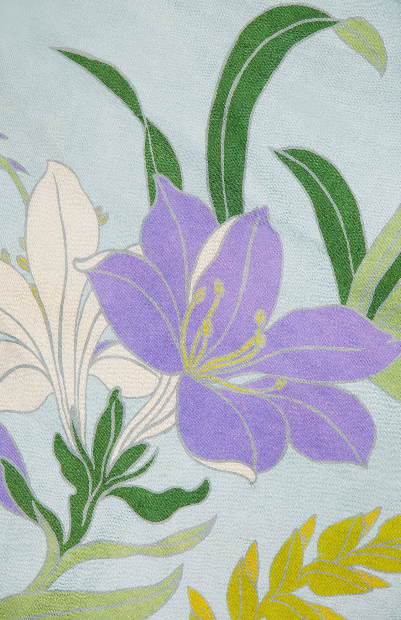 The Alfie Midi Floral Sundress by ALEMAIS features vibrant purple and white flowers with yellow accents and green leaves on a light blue background, capturing the fresh, artistic charm of blooming florals.