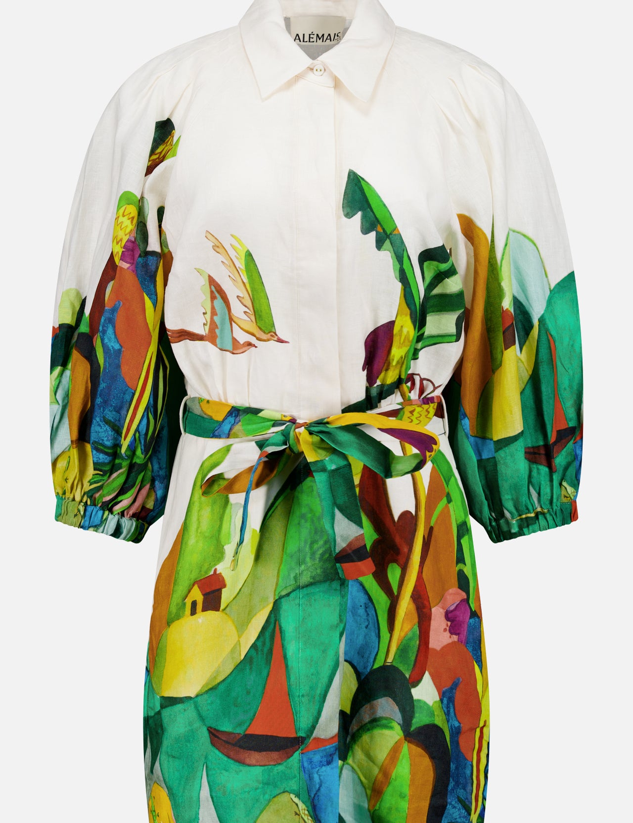 The ALEMAIS Mokshini Artist Collab Mini Dress is a white European linen mini dress with a vibrant abstract tropical landscape print, depicting plants, sailboats, and figures, finished with a matching fabric waist tie.