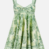 The ALEMAIS Sara Mini Twist Sundress is a sleeveless, flared green and white mini dress with a tropical palm print and decorative green stitching—perfect for sunny days.