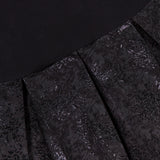 Close-up of the Chara Embellished Neckline Sleeveless Mini Dress by ALICE + OLIVIA, featuring black jacquard fabric with shiny, intricate floral patterns and pleats that transition to a solid black area at the top.