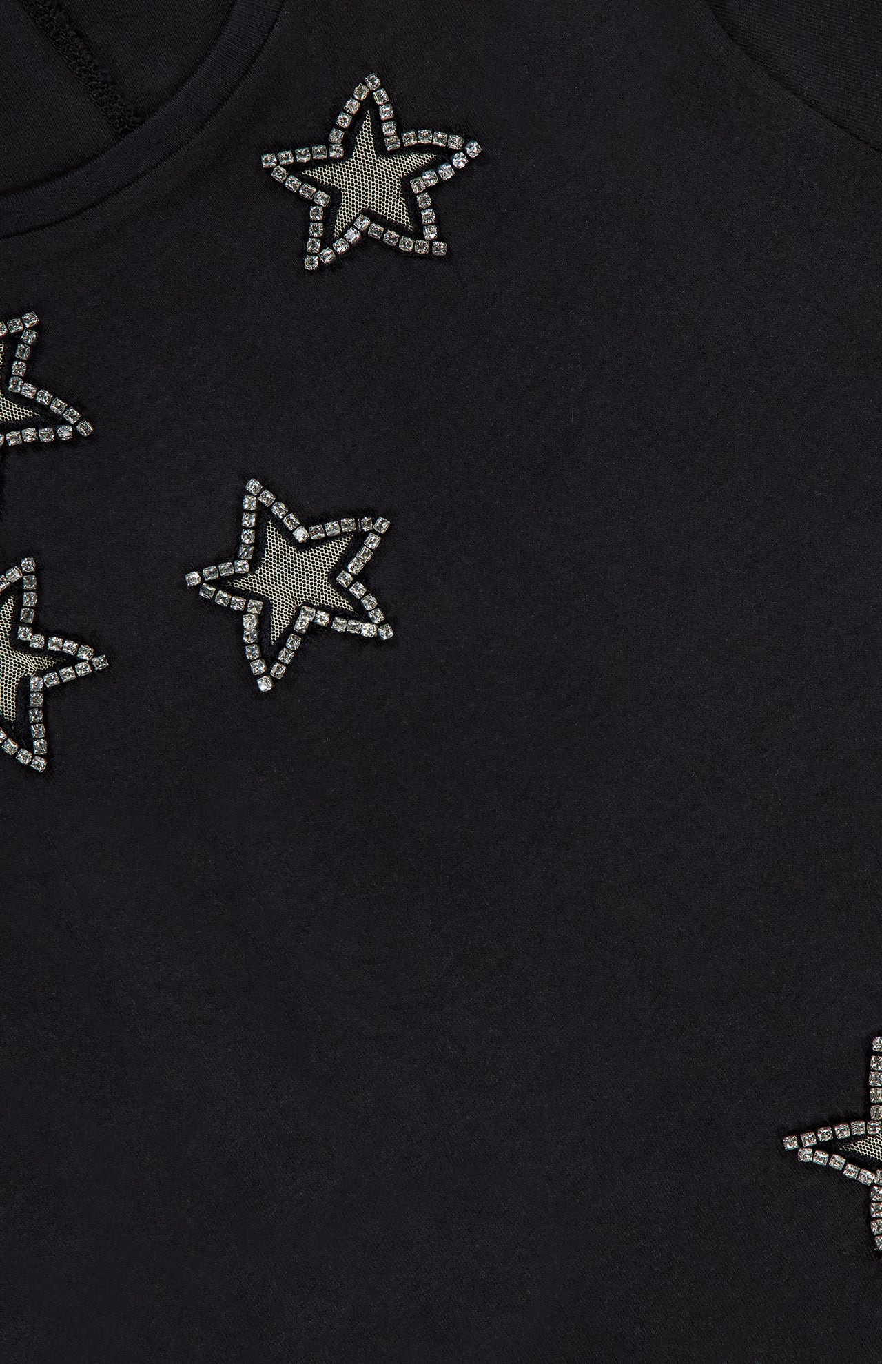 Close-up of ALICE + OLIVIA's Cindy Cropped T-shirt, featuring crystal star cutouts—an eye-catching black top, perfect for a women's night out.