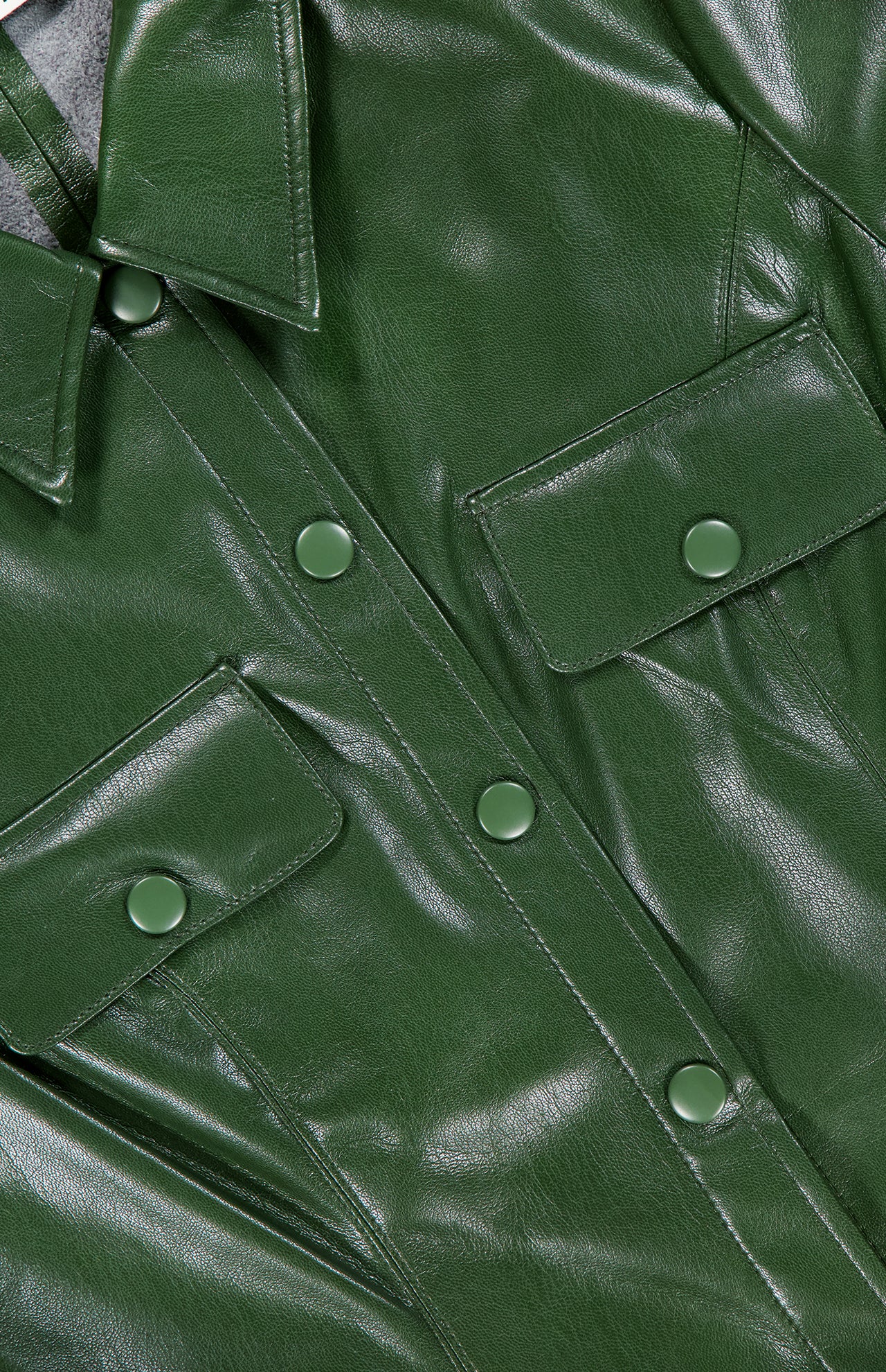 Close-up of the Jamie Vegan Leather Collared Mini Dress by ALICE + OLIVIA, featuring snap buttons, flap chest pockets, glossy dark green finish, and visible stitching—perfect to pair with an A-line silhouette or olive green dress.