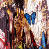 The Katz Maxi Pleated Skirt With Slit by ALICE + OLIVIA features a vibrant, eclectic print of classical figures, blue butterflies, ornate patterns, and map motifs, finished with a decorative blue and yellow trim at the waist.