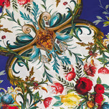 A close-up of the Willa Concealed Placket Top by ALICE + OLIVIA, showcasing vibrant red, yellow, and pink florals with green leaves and gold scrollwork on a white and deep blue crepe de chine fabric.
