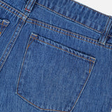 Close-up of the back pocket and waistband of the ALICE + OLIVIA Low Rise Baggy Jean with Applique in Freyja, featuring orange stitching detail on the pocket and belt loops, shown against a white background.