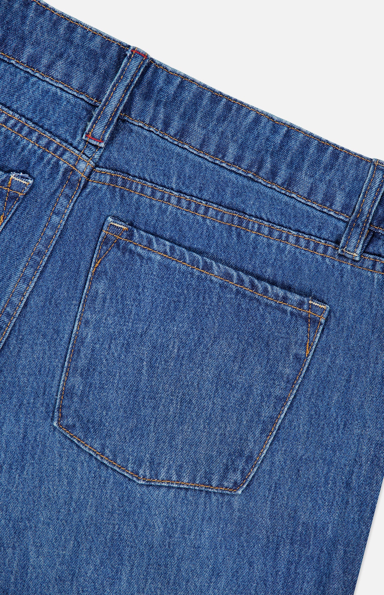 Close-up of the back pocket and waistband of the ALICE + OLIVIA Low Rise Baggy Jean with Applique in Freyja, featuring orange stitching detail on the pocket and belt loops, shown against a white background.