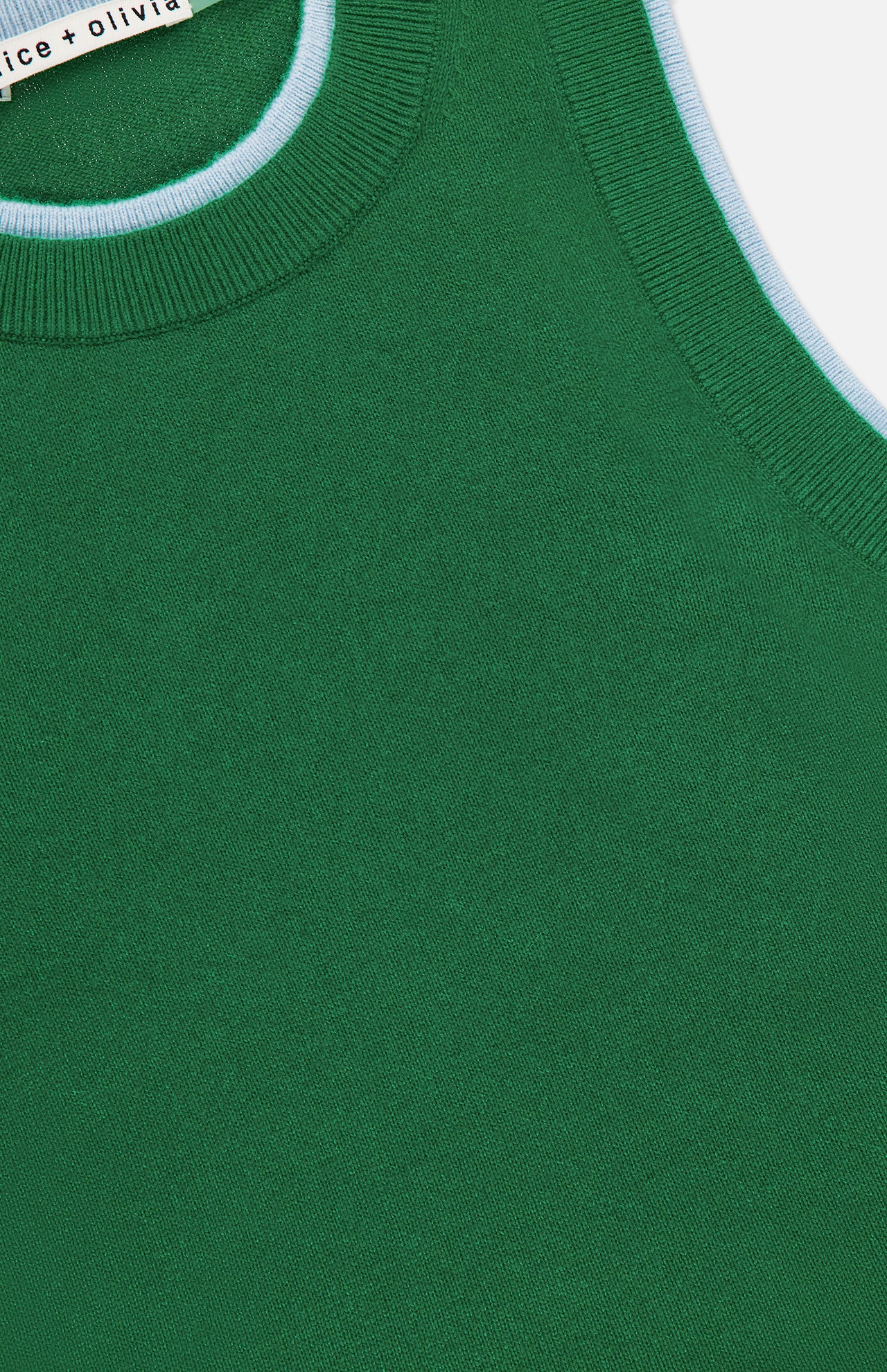 Close-up of the Araceli Two Tone Tank Top by ALICE + OLIVIA, a green sleeveless cropped top with a ribbed neckline and light blue armhole trim. The partially visible label near the top edge shows the designer brand.